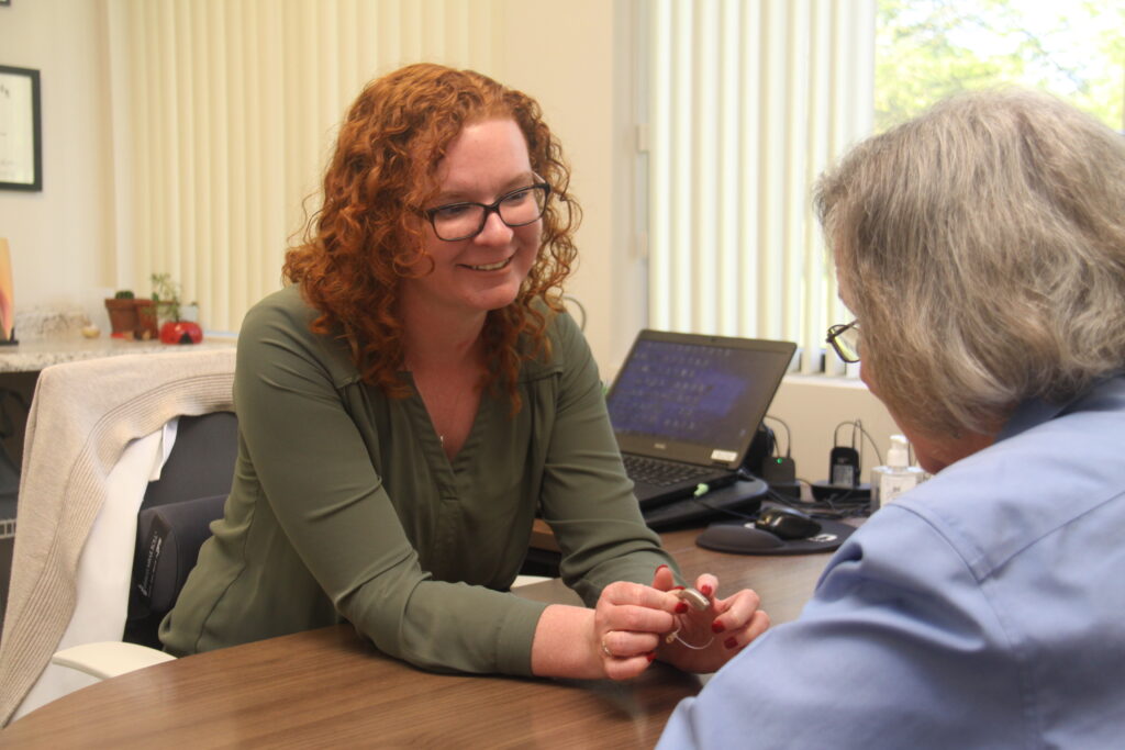 woman talking to another woman with a hearing aid in her hands